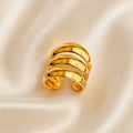 A polished gold wrap ring with three horizontal bands, displayed on a soft, cream-colored satin fabric background.