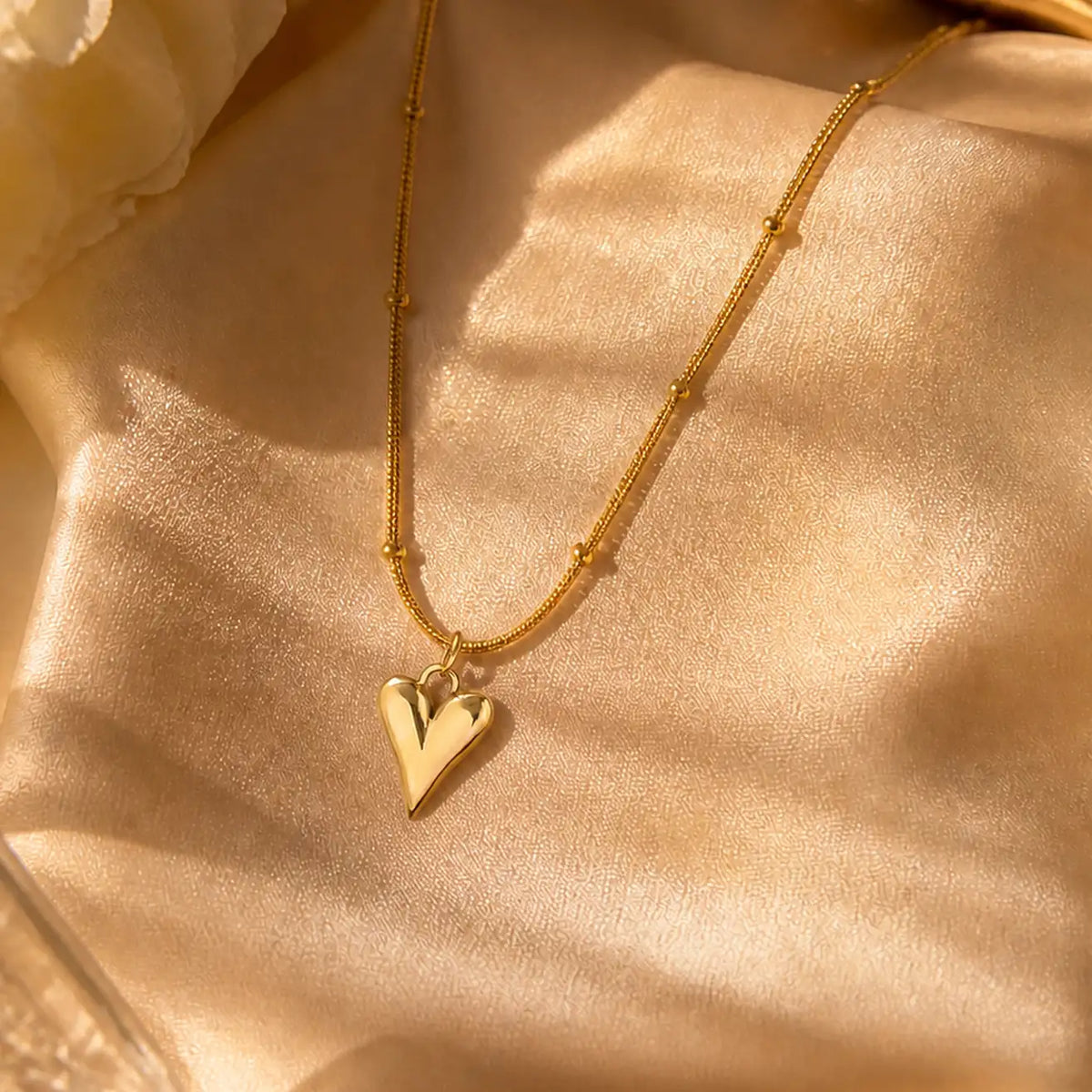 Anti-tarnish gold stainless steel beaded chain necklace with an elongated polished gold heart pendant.