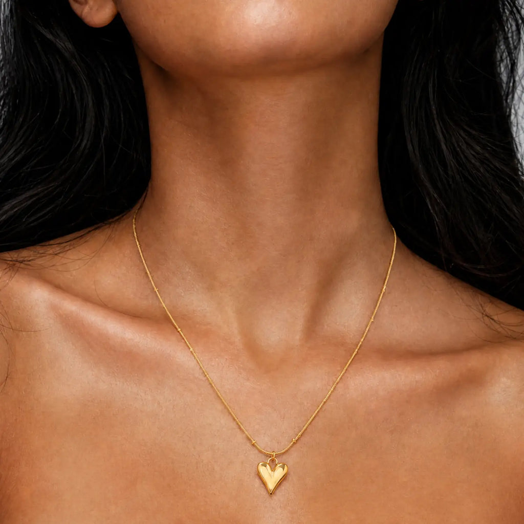 Anti-tarnish gold stainless steel beaded chain necklace with an elongated polished gold heart pendant.