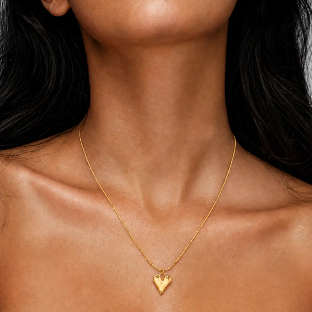 Anti-tarnish gold stainless steel beaded chain necklace with an elongated polished gold heart pendant.