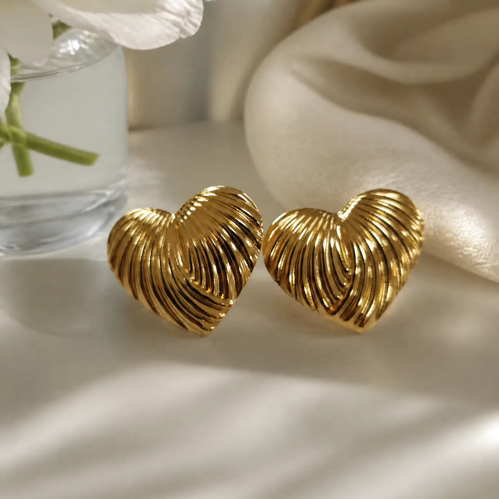 A pair of gold cufflinks shaped like a starfish and a spiral shell, displayed on a dark textured slate surface with scattered gold foil flakes.