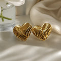 A pair of gold cufflinks shaped like a starfish and a spiral shell, displayed on a dark textured slate surface with scattered gold foil flakes.